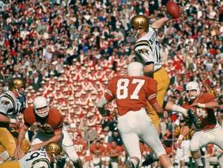 Staubach leaps to pass over Texas rushers.