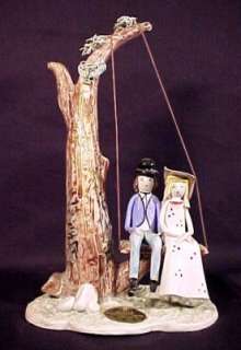   figurine with a man and woman sitting on a tree swing the pieces